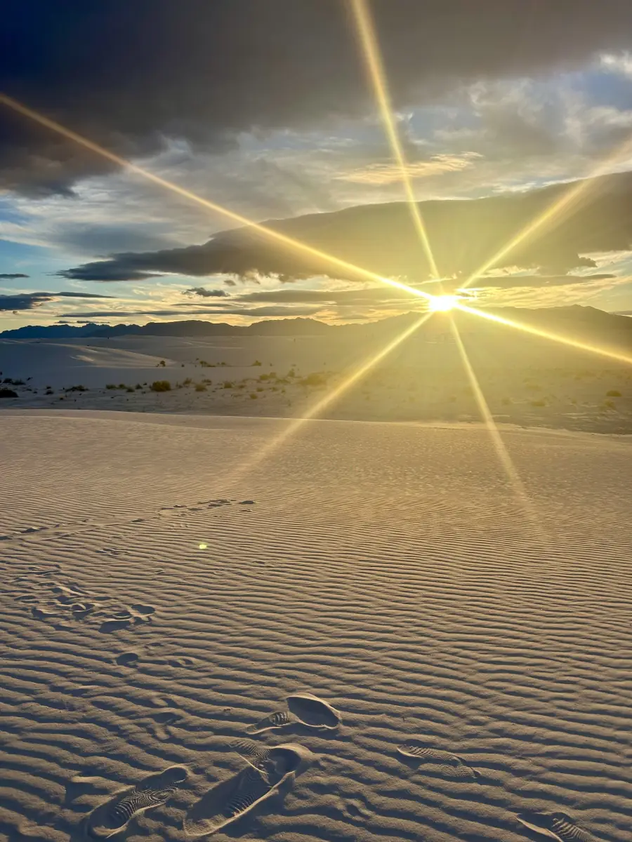 sun setting over white sand dunes
